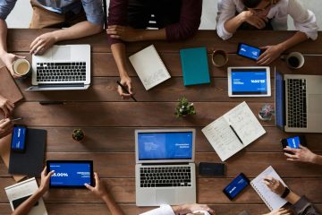 Overhead view of a diverse team in a business meeting using laptops and tablets.
